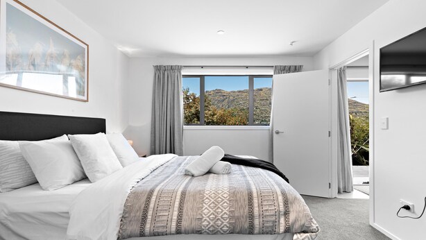 Un dormitorio con cama, un ventanal grande y una puerta que da a un espacio exterior.