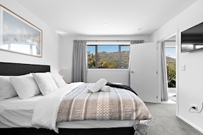 A bedroom with a bed, a large window, and a door leading to an outdoor area.