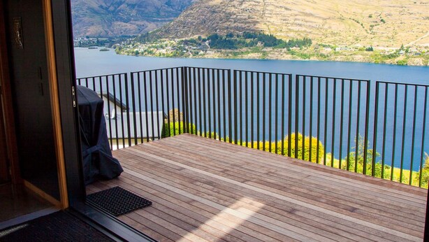 A room with a large window overlooking a lake and mountains.