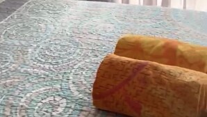 Hotellihuone, jossa on sänky, yöpöytä ja ikkuna, jossa on läpikuultavat verhot.