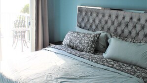 Un dormitorio con una cama grande, un ventilador de techo y vistas al exterior a través de una puerta corrediza.