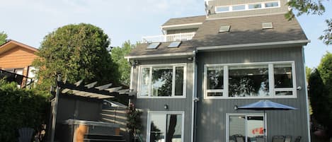 Et toetagers hus med en patio, et boblebad og et overdækket siddeområde.