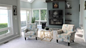 Un salón amplio con dos sillones estampados, una mesa de centro de cristal y un ventilador de techo.