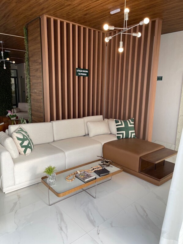 A modern living room with a sectional sofa, a glass coffee table, and a wooden slatted wall.