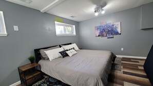 A bedroom with a bed, a nightstand, a window, a ceiling fan, and a patterned rug. - Comfortable 4 Bedroom / 1.5 Bathroom Home (Ypsilanti)