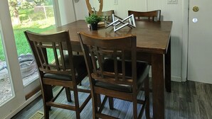 A dining area with a wooden table and chairs, a potted plant, and a decorative piece on the table. - Comfortable 4 Bedroom / 1.5 Bathroom Home (Ypsilanti)