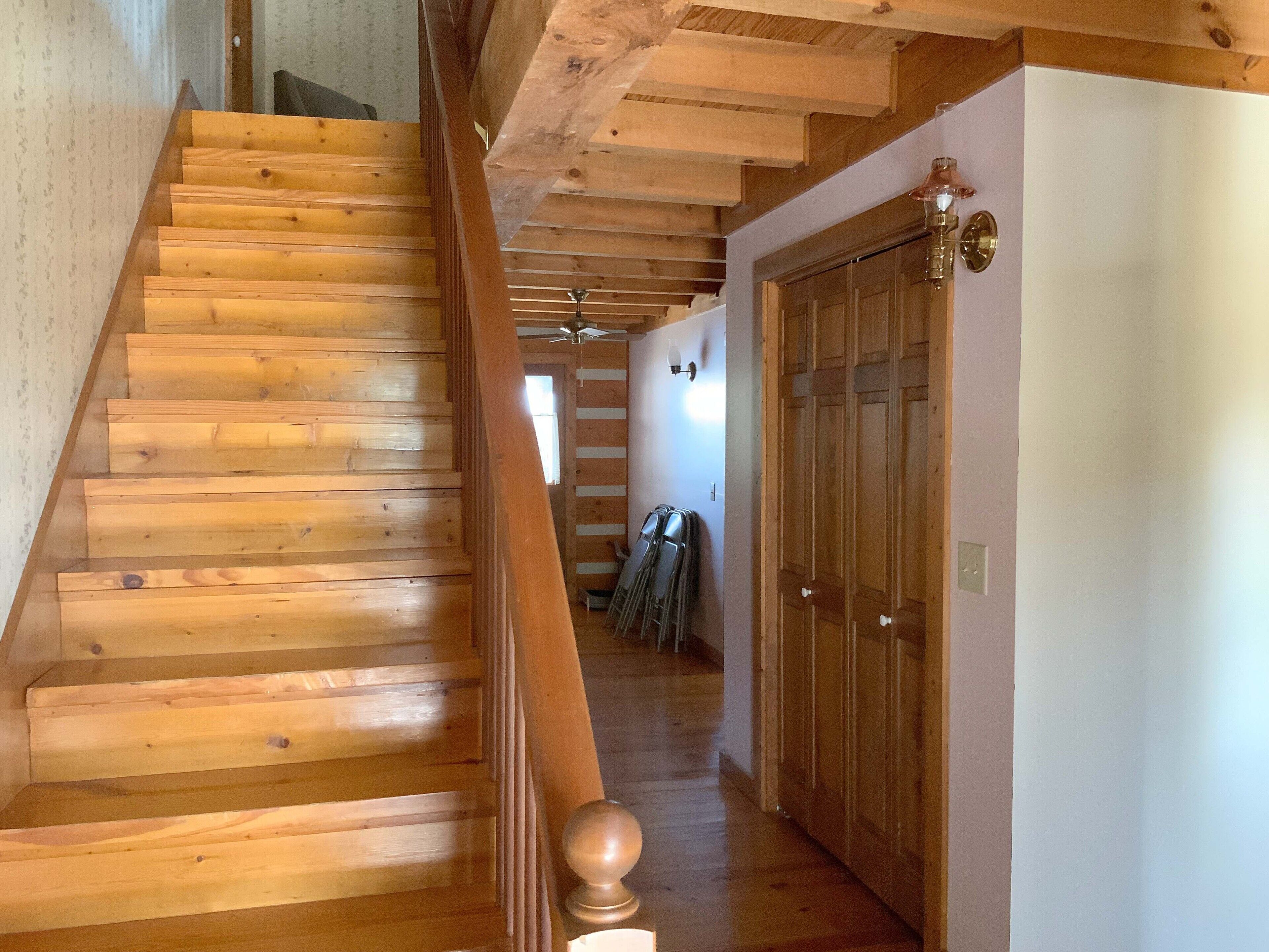 Un escalier en bois avec une rampe et un ventilateur de plafond.