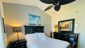 A bedroom with a bed, a nightstand, a dresser, a ceiling fan, a painting, a mirror, and a lamp. - Great 1 BDR Condo in the center of Myrtle Beach (Myrtle Beach)