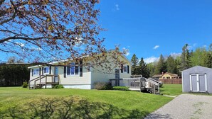 A two-story house with a front deck, a small shed, and a well-maintained lawn. - Ranch home with 3 bedrooms upstairs and 1 down. Refurnished June of 2022 (St. Ignace)