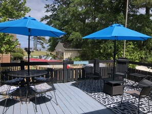 Un patio al aire libre con dos sombrillas azules, suelo estampado y mobiliario exterior.