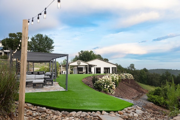 Una casa moderna con patio coperto, prato curato e vista sul paesaggio circostante.