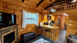 Ein rustikales Holzhaus-Interieur mit Küche, Bar und Sitzgelegenheiten.