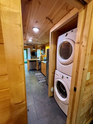 A wooden interior with a kitchen area, a washing machine, and a tiled floor. - Serenity Ridge Cabin B: Couple's Retreat + Hot Tub (Mill Spring)