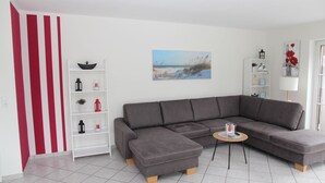 Una sala de estar moderna con un sofá seccional gris, un estante blanco y una pequeña mesa redonda.