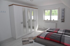 Une chambre à coucher comprenant un lit, une armoire, un radiateur et une fenêtre donnant sur un espace verdoyant.
