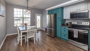 A modern kitchen with white cabinetry, a stainless steel refrigerator, a built-in oven, and a dining area with a wooden table and chairs. - ⭐️⭐️⭐️⭐️⭐️ Home next to KHP/Downtown (Lexington)