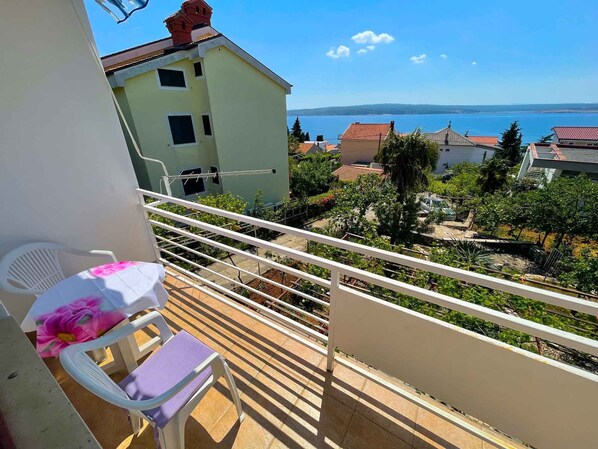 Relax on the balcony with a scenic view of the surrounding landscape, featuring a body of water and distant hills.