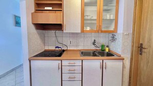 Une cuisine de taille réduite, équipée d’une cuisinière, d’un évier et de meubles de rangement en bois.