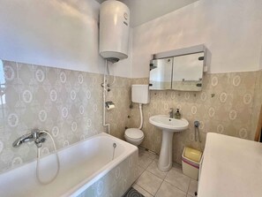 Bathroom features a bathtub, sink, and toilet, with a patterned tile backsplash and a mirror above the sink.