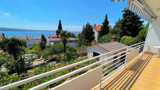 Un balcon donnant sur une zone côtière, avec vue sur des maisons et des arbres.