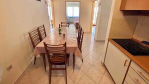 Un coin repas avec une table dressée pour six personnes, une bouteille de champagne et un verre posé sur la table.