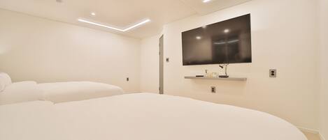 Un dormitorio moderno con una cama grande, un televisor de pantalla plana en la pared e iluminación empotrada en el techo.
