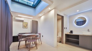 A modern hotel room with a skylight, a dining area with a table and chairs, a built-in kitchen with a sink and mirror, and a walk-in closet. - Green B Hotel Busan Seomyeon (Busan)