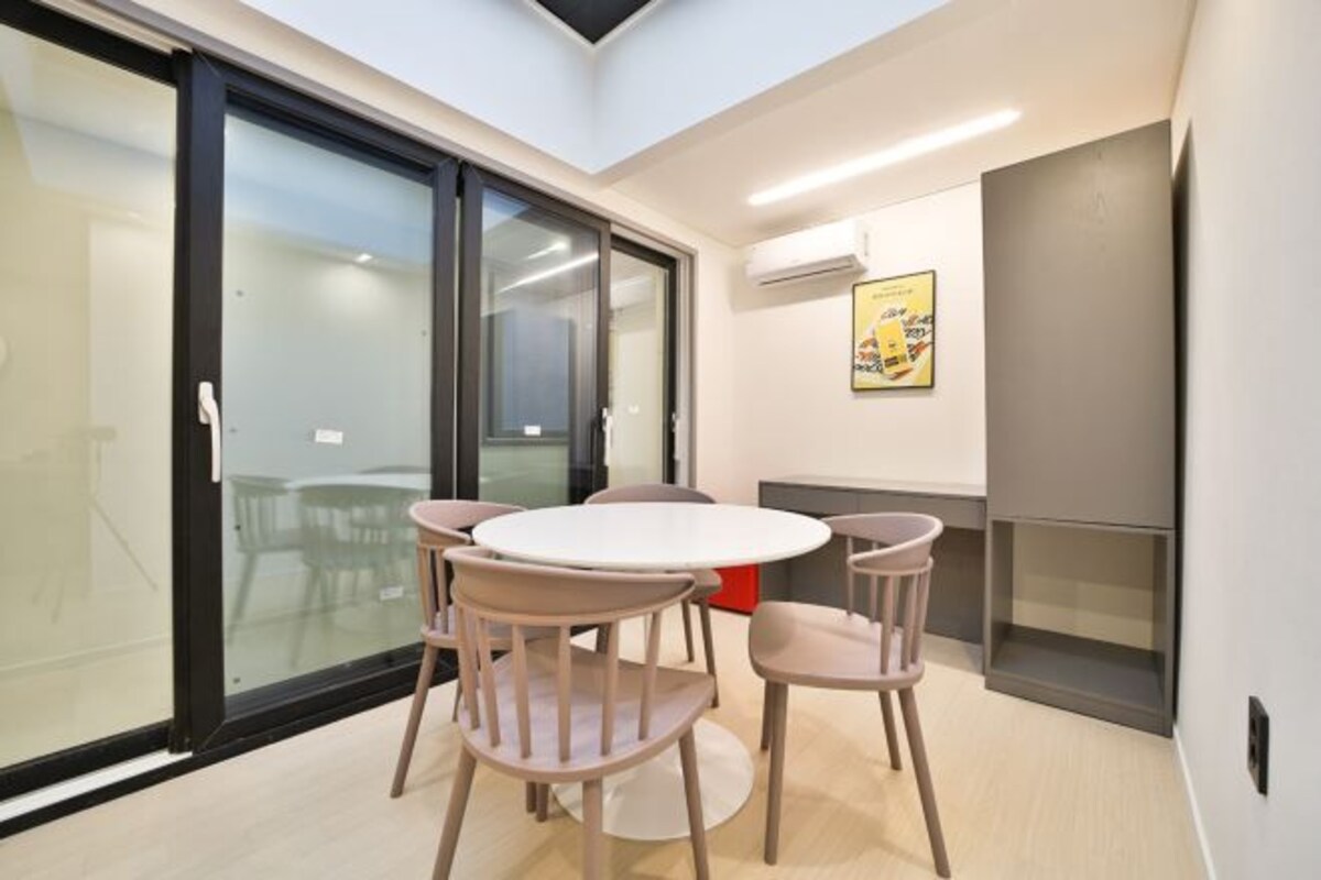 A modern meeting room with a glass partition, a round table, and four chairs.