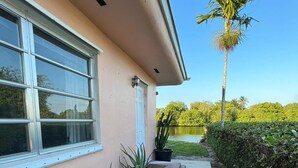 A house with a concrete pathway leading to a door, surrounded by potted plants and a palm tree. - 1bed apt in Hollywood&31st str. Independent apt with amazing backyard. (Hollywood)