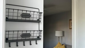 A room with a grey sofa, a yellow pillow, and two black wall-mounted racks. - 1bed apt in Hollywood&31st str. Independent apt with amazing backyard. (Hollywood)