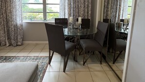 A hotel room with a dining table, four chairs, a bed, a large window with curtains, and a ceiling fan. - 1bed apt in Hollywood&31st str. Independent apt with amazing backyard. (Hollywood)