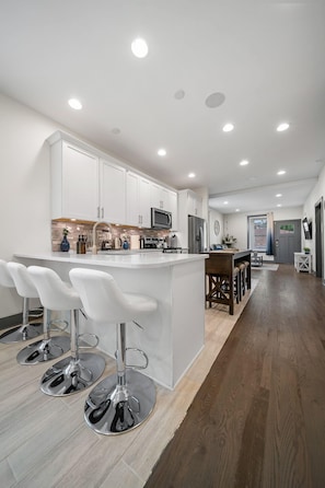 A modern kitchen with white cabinets, stainless steel appliances, and a central island with bar stools.