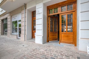 Ein Gebäude mit großen Holztüren und -fenstern, eine Kopfsteinpflasterstraße und ein Schild, das auf ein Geschäft hinweist.