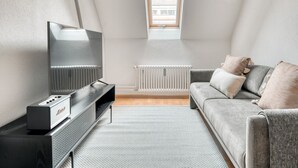 Una sala de estar moderna con televisor de pantalla plana, sofá gris y un radiador.