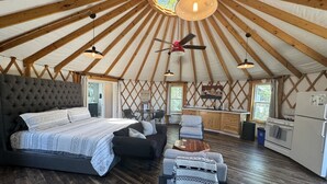 A spacious tent with a large bed, a dining area, and a kitchen. - Glamping Yurt + Luxury Bath at Serenity Ridge (Mill Spring)