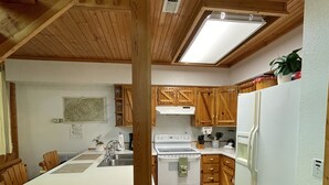 A compact kitchen with wooden cabinets, a white countertop, and a built-in stove. - Mountain Memory Cabin (Topton)