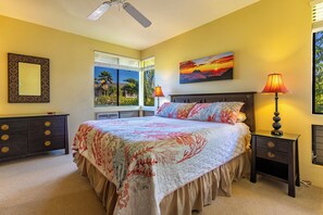 A bedroom with a bed, two nightstands, a ceiling fan, a window with blinds, and a painting on the wall.