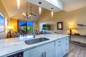 A modern kitchen with a large island, a built-in dishwasher, and a ceiling fan.