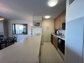 A modern kitchen with wooden cabinets, a white countertop, and a built-in microwave.