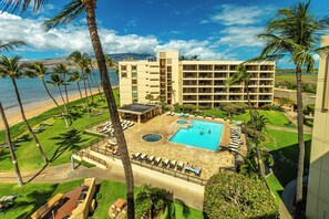 A hotel with a pool, palm trees, and a view of the ocean.