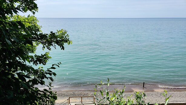 Unes escales de fusta que condueixen a una platja amb aigua turquesa cristal·lina i una vista de l'oceà.