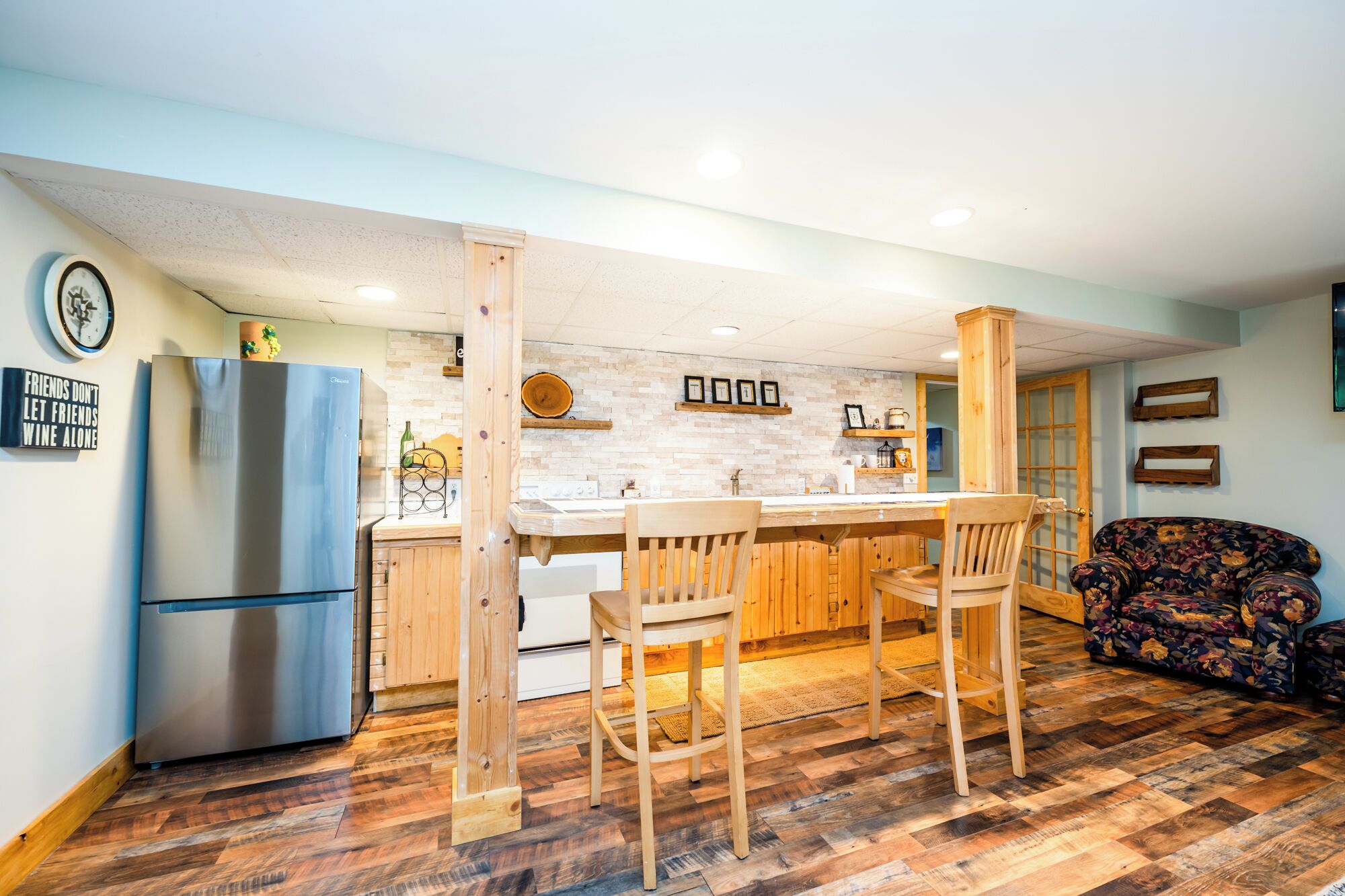 Une cuisine moderne avec un îlot central, des chaises en bois et un réfrigérateur.