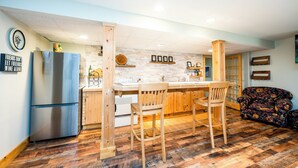 Una cuina moderna amb una illa central, cadires de fusta i un frigorífic.