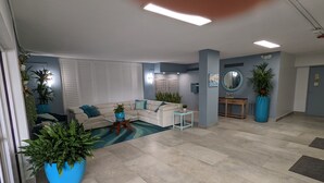 A spacious living room with a large sectional sofa, a coffee table, and several potted plants. - Beautiful direct ocean front beach access condo (Satellite Beach)
