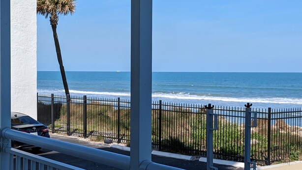 A balcony with a view of the ocean, a palm tree, and a fence. - Beautiful direct ocean front beach access condo (Satellite Beach)