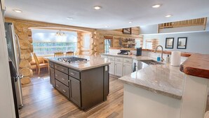 A kitchen with a central island, wooden flooring, and a stone accent wall.