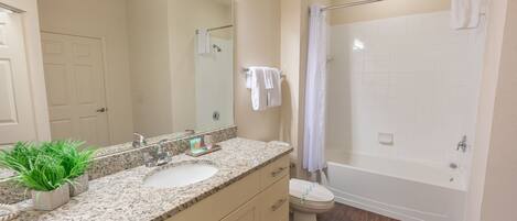 A bathroom with a sink, mirror, toilet, and shower.