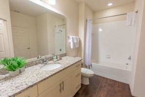 Baño con lavamanos, espejo, inodoro y ducha.