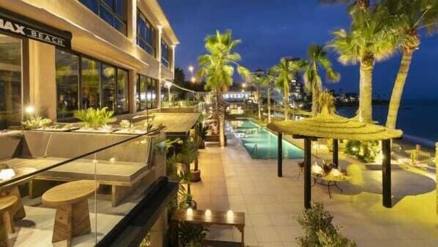 Et hotel med udendørs siddepladser, pool og palmer.