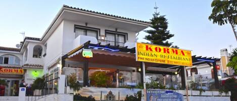 A building with a sign for 'Korma Indian Restaurant' and a welcome banner.